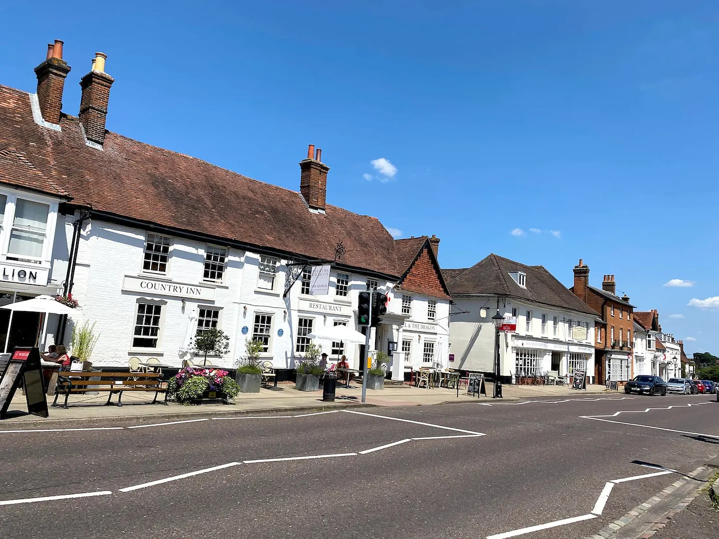Odiham High Street on a sunny day, lined with old pubs and houses