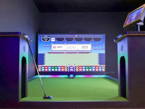 An interactive mini golf lane with a big screen at the end, lit up inside Ballerz Clubhouse