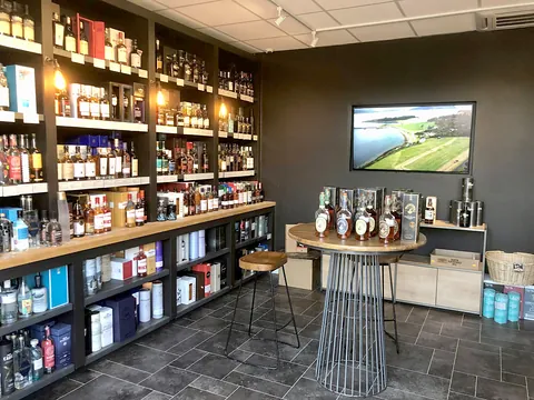 Inside the Caviste wine shop at Newlyns, with shelves of bottles lit along a dark wall