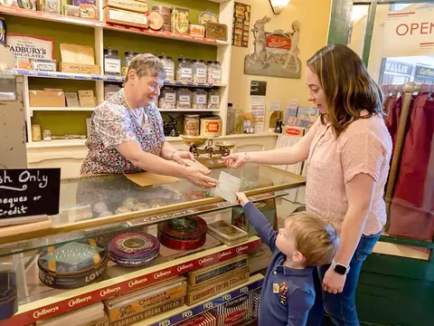 A child and parent buying sweets across the counter of the old-fashioned sweet shop at Milestones