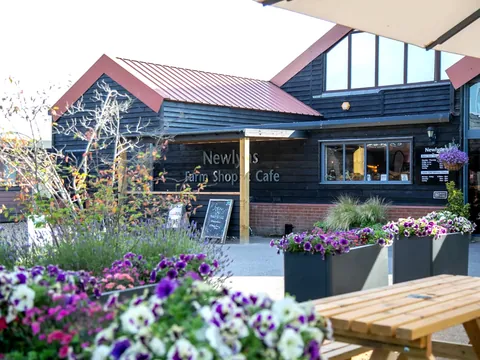 The timber-clad farm shop and café building at Newlyns, with flower planters outside