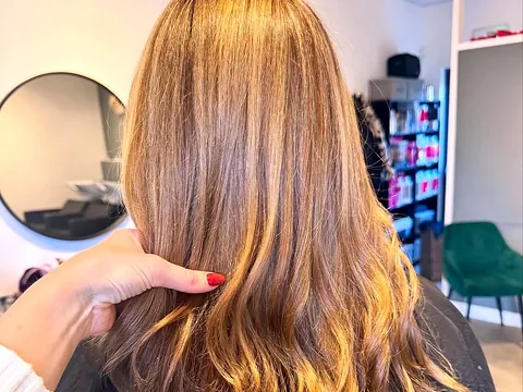 A glossy caramel balayage at Studio K, with the salon mirrors and green chairs behind