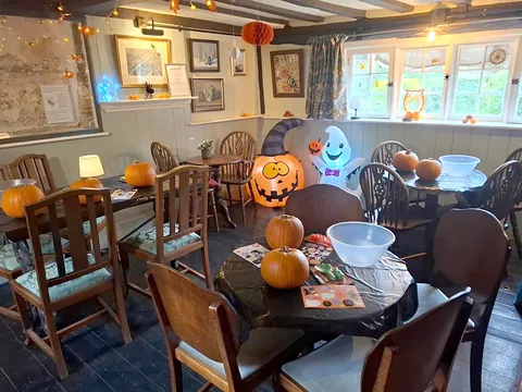 The beamed bar room inside the Bell in Odiham, with wooden tables and chairs, pictures on the walls and Halloween decorations