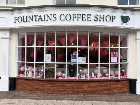 The shopfront of Fountains Coffee Shop on Odiham High Street, with a big bay window decorated with pink bunting and balloons